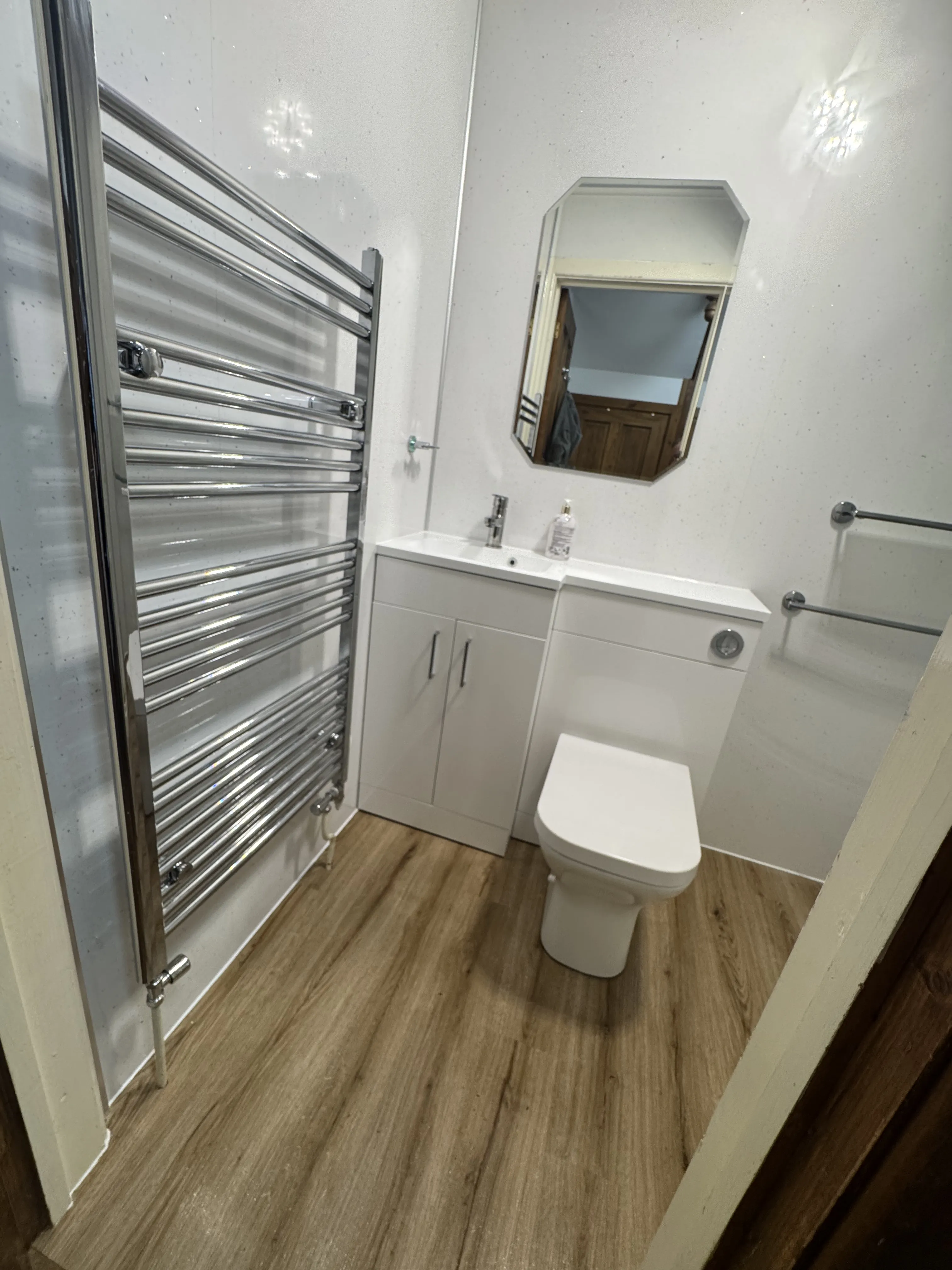 Modern white en-suite with heated towel rail and vanity unit